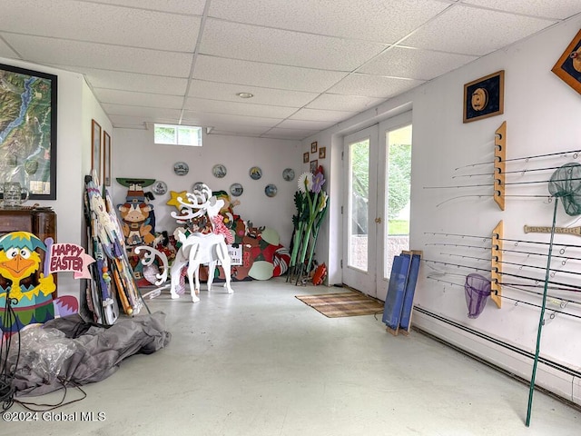 misc room with a paneled ceiling, concrete floors, a baseboard radiator, and french doors