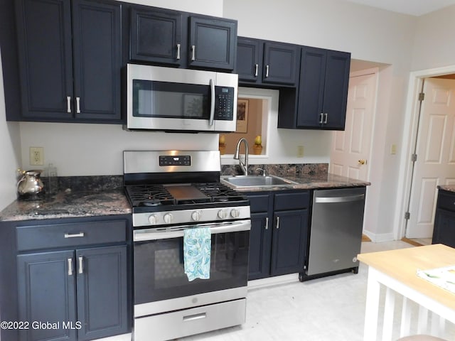 kitchen featuring sink, blue cabinets, stainless steel appliances, and dark stone counters