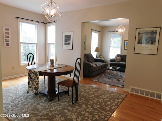 dining area featuring hardwood / wood-style floors, a healthy amount of sunlight, and a chandelier