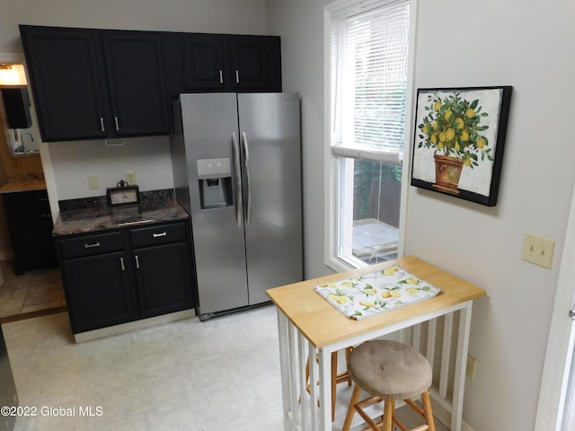 kitchen featuring stainless steel fridge and dark stone countertops