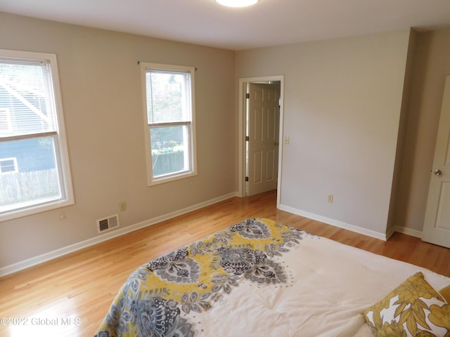 bedroom with hardwood / wood-style floors and multiple windows