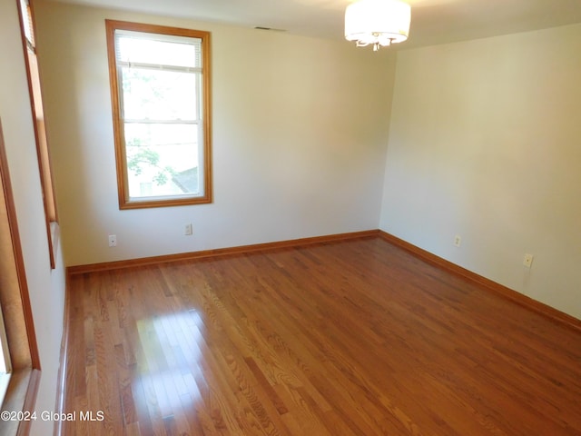 unfurnished room featuring hardwood / wood-style flooring and a notable chandelier