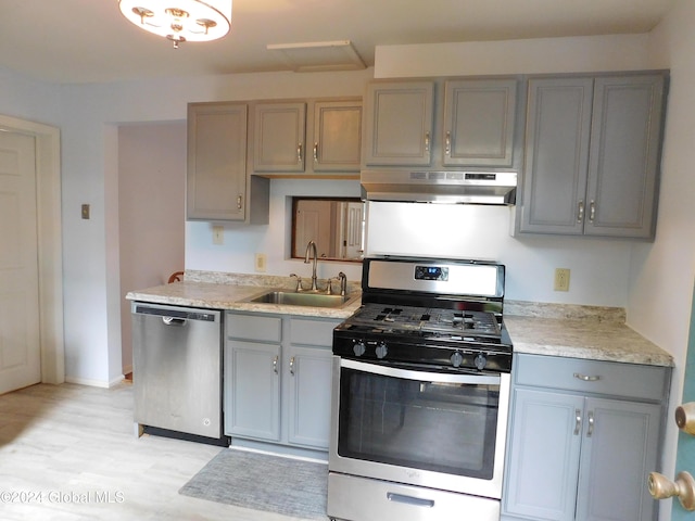 kitchen featuring sink, stainless steel appliances, light hardwood / wood-style floors, gray cabinets, and exhaust hood