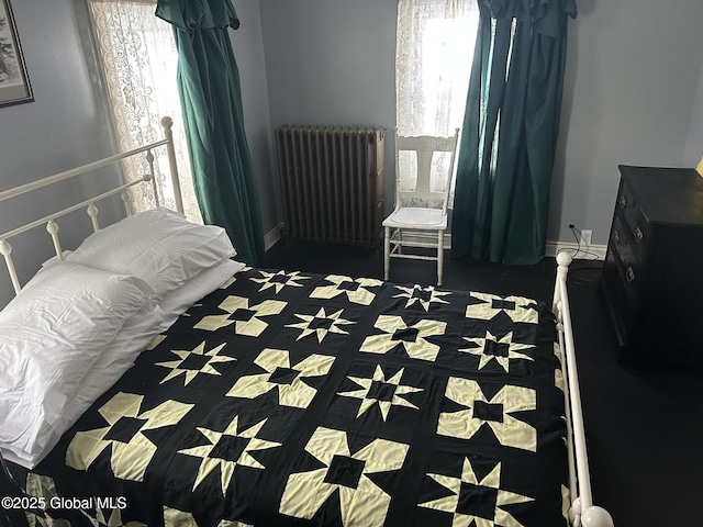 bedroom with radiator heating unit and multiple windows