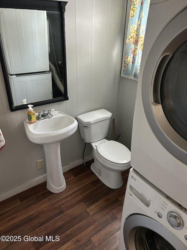 bathroom featuring stacked washer and dryer, sink, toilet, and hardwood / wood-style floors