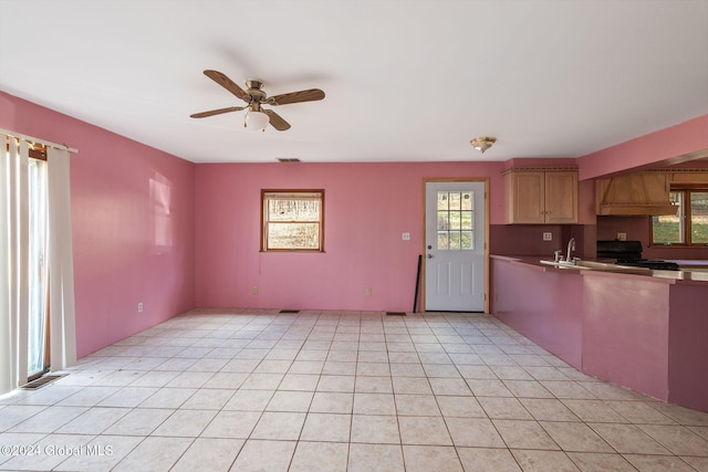 kitchen featuring light tile patterned flooring, custom range hood, black range, and ceiling fan