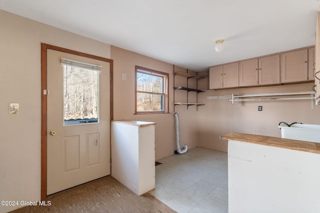 clothes washing area with cabinets and sink