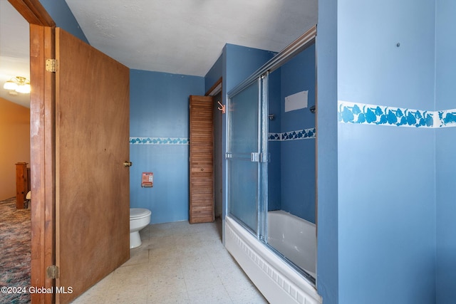 bathroom featuring toilet, tile walls, and bath / shower combo with glass door