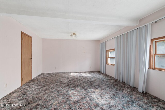 unfurnished room with beamed ceiling and carpet floors