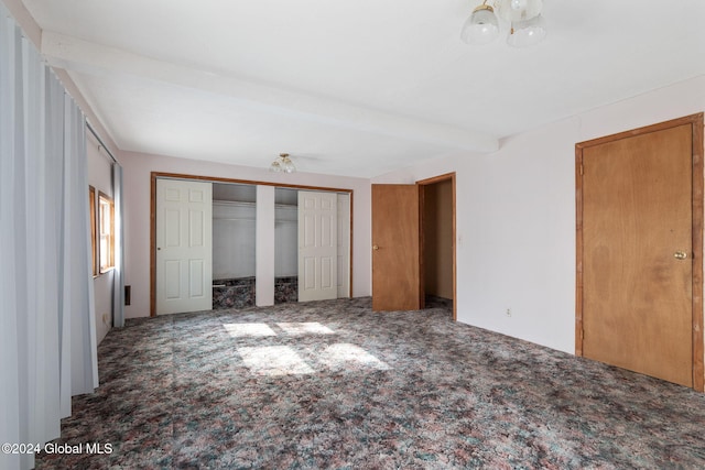 unfurnished bedroom with beam ceiling and carpet floors