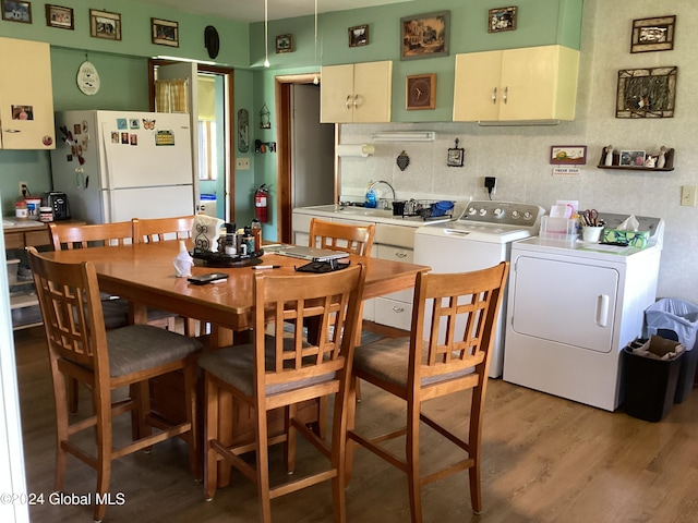 dining room with wood-type flooring, sink, and washing machine and dryer