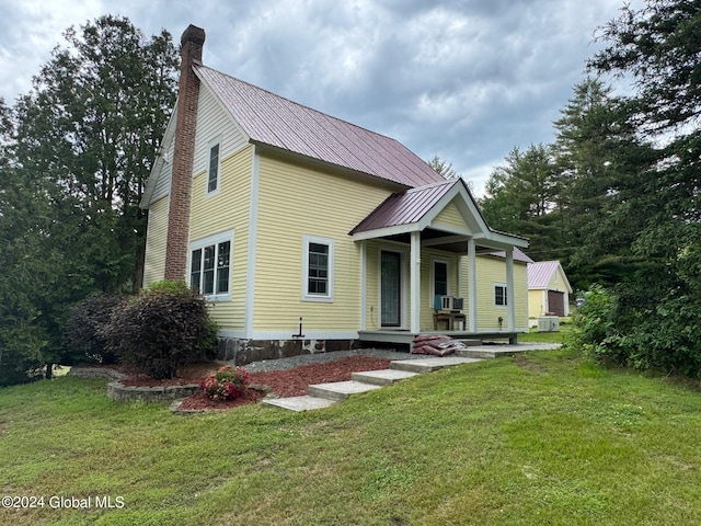 view of front of property with a front lawn, metal roof, covered porch, and a chimney