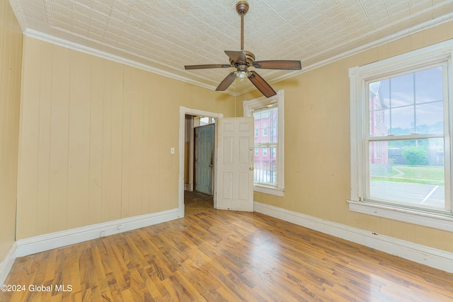 unfurnished room featuring wood-type flooring, ornamental molding, ceiling fan, and plenty of natural light