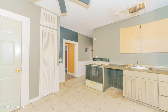 kitchen with white electric range oven, light tile patterned floors, and sink