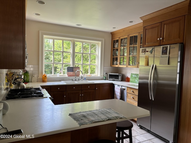 kitchen with a breakfast bar, sink, kitchen peninsula, stainless steel refrigerator, and backsplash