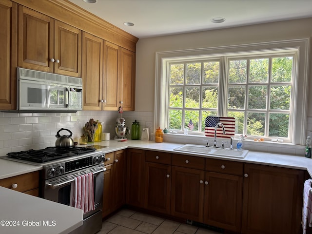 kitchen with stainless steel range, a healthy amount of sunlight, decorative backsplash, and sink