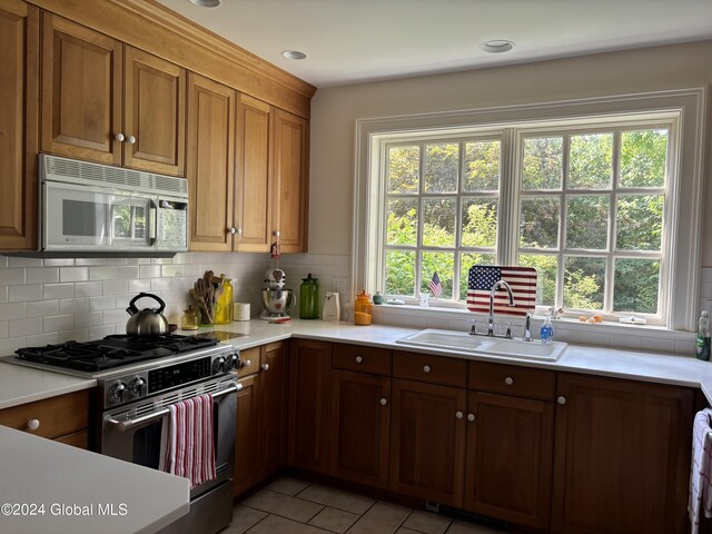 113 S William St, Johnstown, NY 12095 - kitchen featuring light countertops, light tile patterned floors, stainless steel appliances, decorative backsplash, and a sink