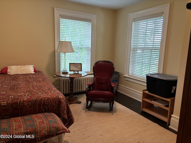 bedroom with radiator heating unit, multiple windows, and hardwood / wood-style floors