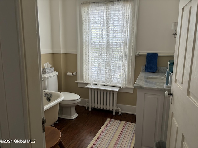 bathroom with toilet, vanity, a tub, hardwood / wood-style floors, and radiator