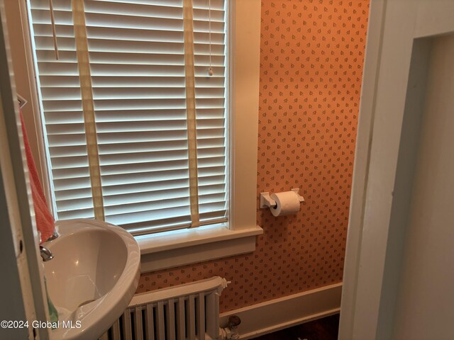 113 S William St, Johnstown, NY 12095 - bathroom featuring radiator heating unit, wallpapered walls, and a sink