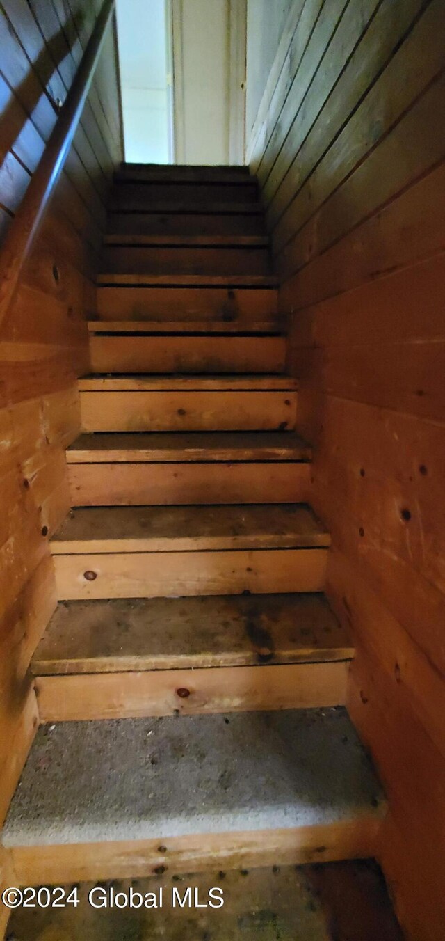 staircase featuring wood walls