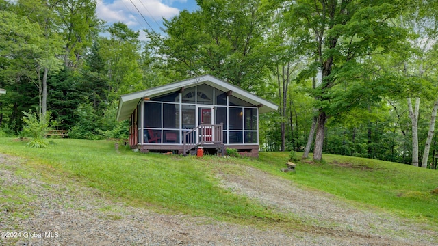 rear view of house with a sunroom, driveway, and a lawn