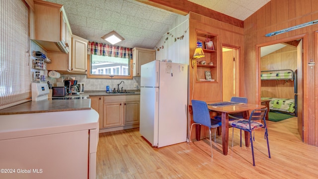 kitchen with freestanding refrigerator, a sink, light wood-type flooring, wood walls, and light brown cabinetry