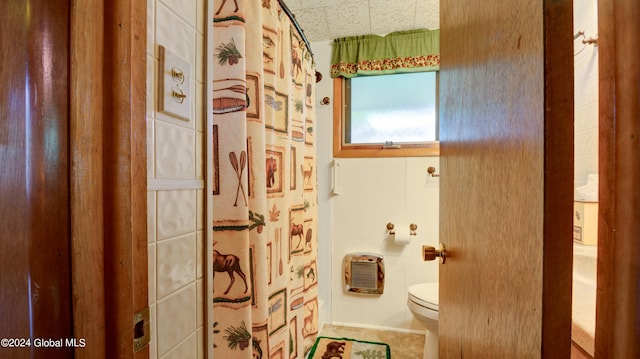 full bath featuring toilet, curtained shower, tile walls, and tile patterned flooring