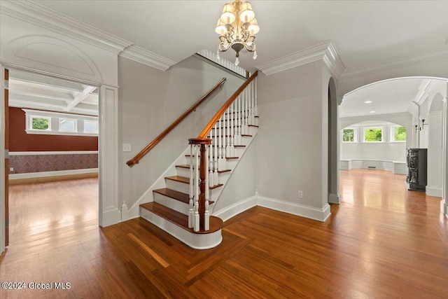 stairs featuring an inviting chandelier, crown molding, and plenty of natural light