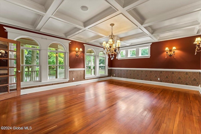 unfurnished room with beam ceiling, coffered ceiling, an inviting chandelier, and hardwood / wood-style flooring