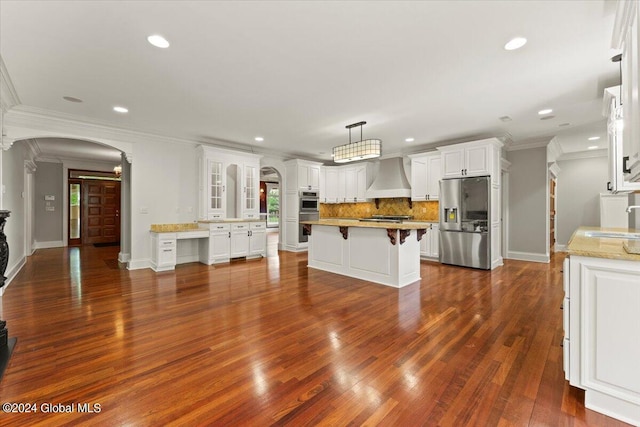 kitchen with custom exhaust hood, stainless steel appliances, a kitchen island, decorative backsplash, and white cabinetry