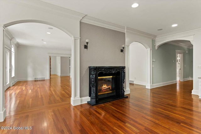 unfurnished living room featuring decorative columns, a fireplace, wood-type flooring, and ornamental molding