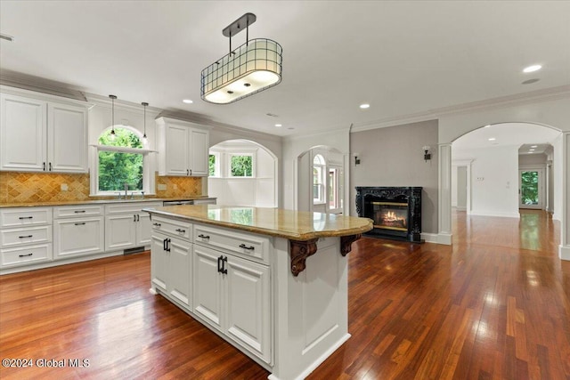 kitchen with white cabinetry, hanging light fixtures, a kitchen island, and a premium fireplace