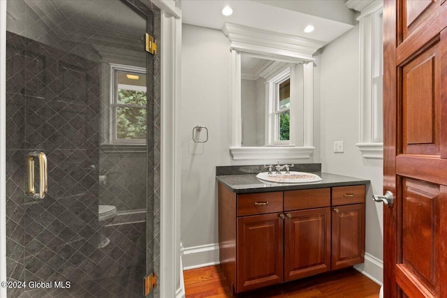 bathroom with ornamental molding, walk in shower, hardwood / wood-style floors, and vanity