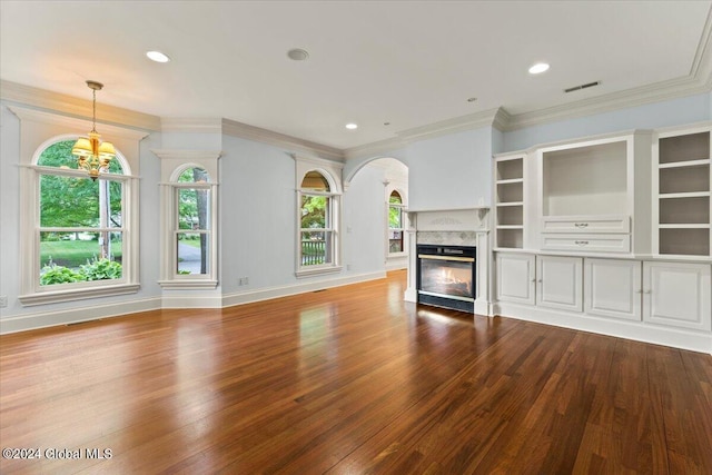 unfurnished living room with a premium fireplace, hardwood / wood-style floors, a notable chandelier, and ornamental molding