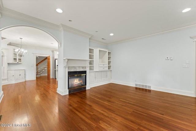 unfurnished living room with a premium fireplace, crown molding, wood-type flooring, and a notable chandelier