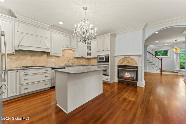 kitchen featuring white cabinetry, a center island, stainless steel appliances, light stone counters, and decorative light fixtures