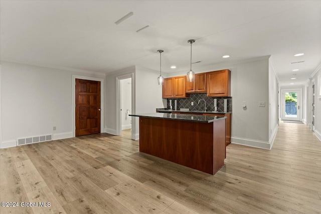 kitchen with light hardwood / wood-style floors, hanging light fixtures, ornamental molding, sink, and tasteful backsplash