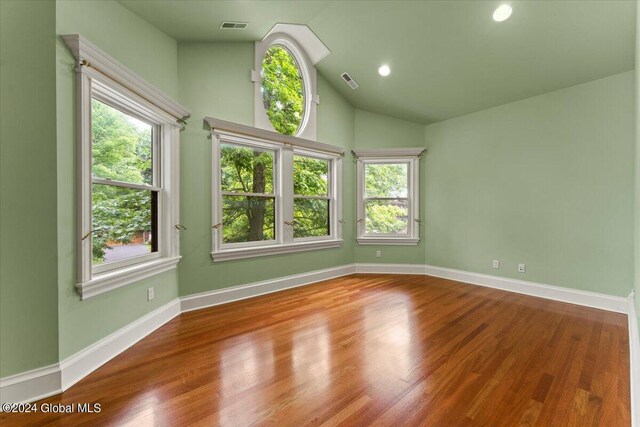 unfurnished room featuring hardwood / wood-style floors and lofted ceiling