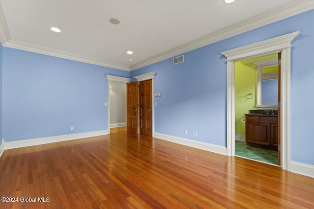 unfurnished bedroom with ornamental molding, connected bathroom, sink, and hardwood / wood-style flooring