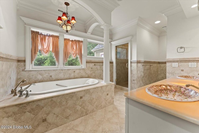 bathroom featuring plus walk in shower, an inviting chandelier, decorative columns, vanity, and ornamental molding