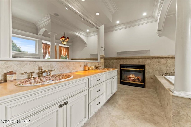 bathroom with ornamental molding, a tub to relax in, and vanity