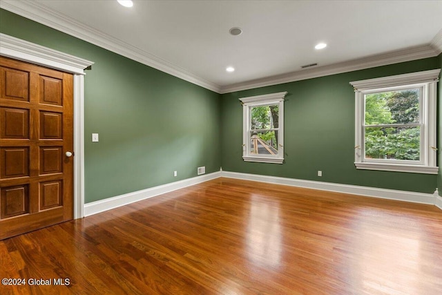 spare room with ornamental molding, a wealth of natural light, and wood-type flooring