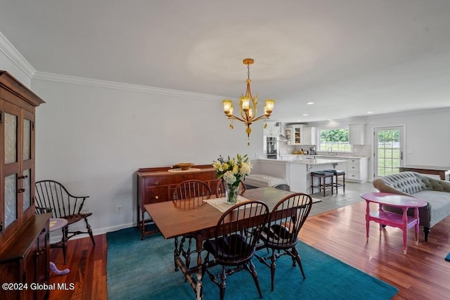 dining area with crown molding, wood-type flooring, and a notable chandelier