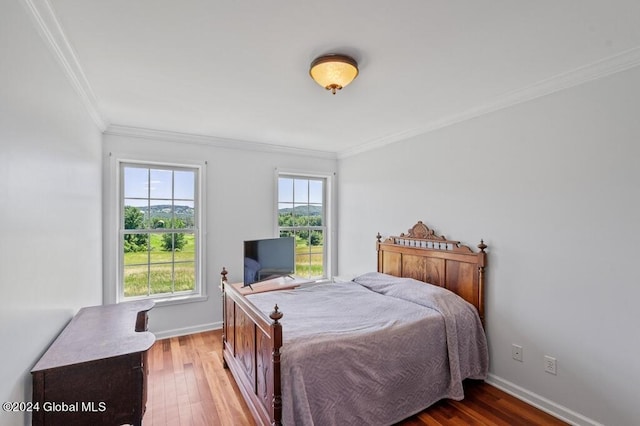 bedroom featuring wood-type flooring, ornamental molding, and multiple windows