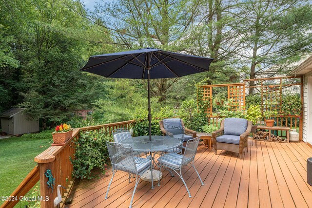 wooden terrace featuring a storage unit, a yard, an outbuilding, and outdoor dining space
