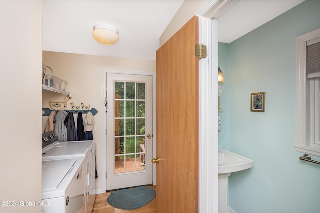 clothes washing area with baseboards, laundry area, light wood-type flooring, and washing machine and clothes dryer