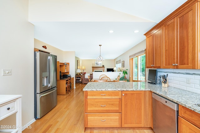 kitchen with decorative backsplash, a peninsula, open floor plan, light wood-type flooring, and stainless steel appliances