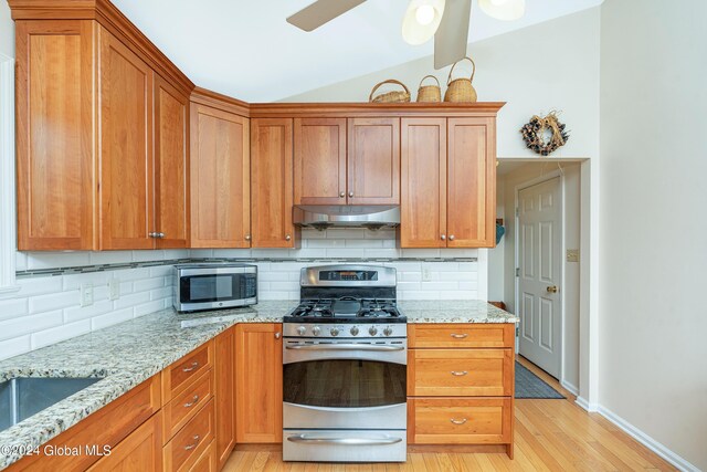 kitchen with backsplash, lofted ceiling, under cabinet range hood, and stainless steel appliances