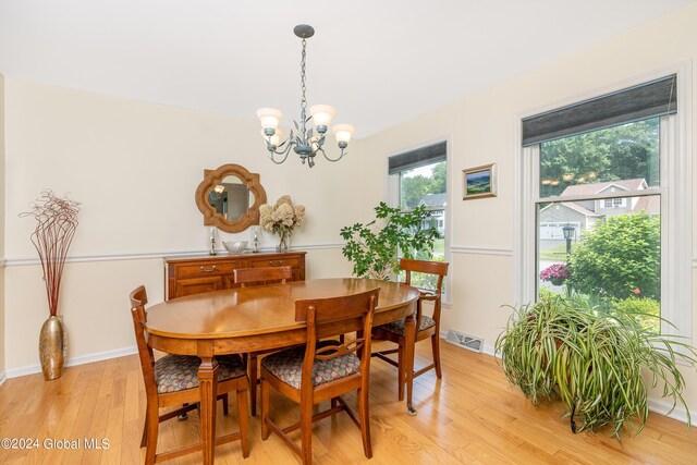 dining room with a chandelier, baseboards, visible vents, and light wood finished floors